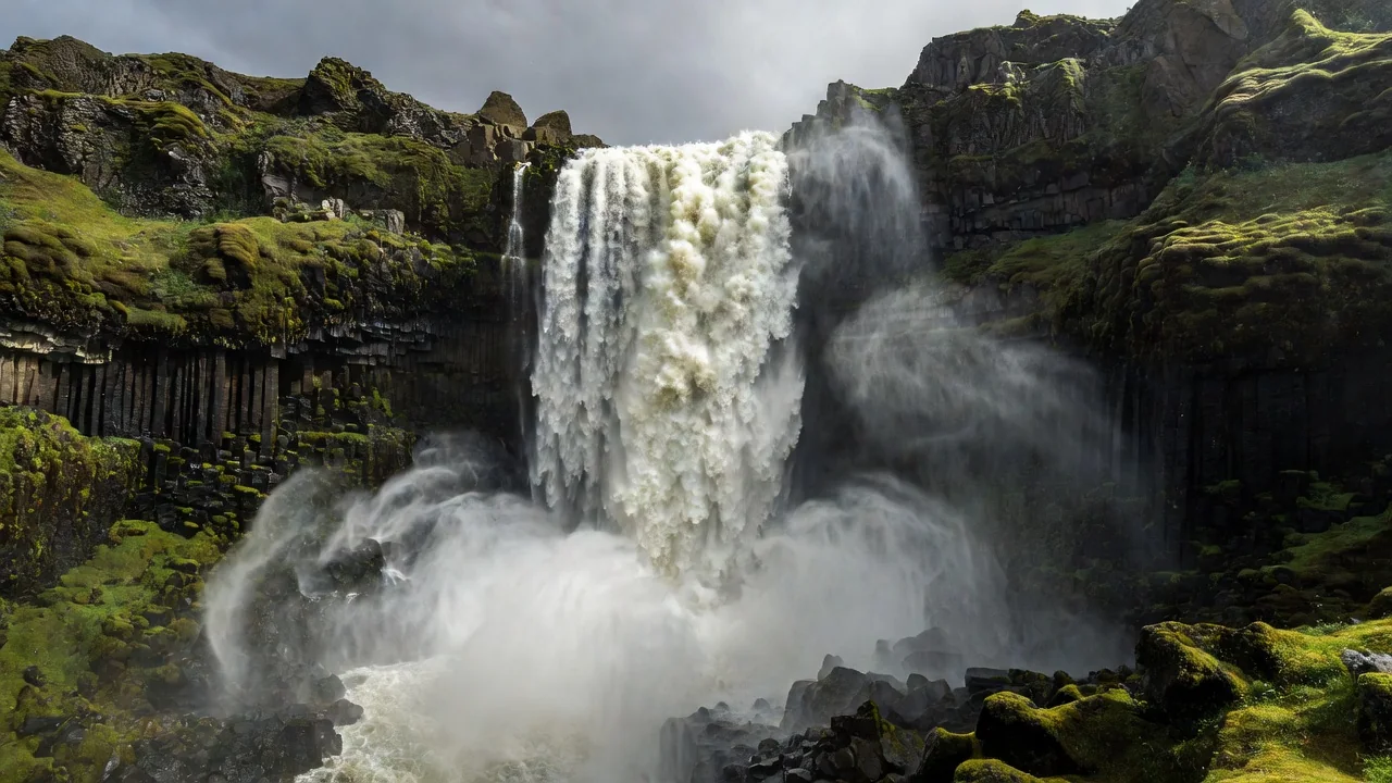 Cascata islandesa entre rochas verdes e musgo